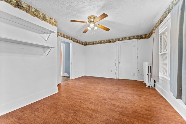 unfurnished bedroom with radiator, ceiling fan, hardwood / wood-style floors, and a textured ceiling