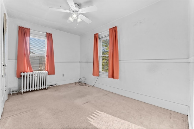 carpeted spare room with radiator, ceiling fan, and plenty of natural light