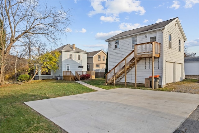 rear view of house with a yard, a garage, and a deck