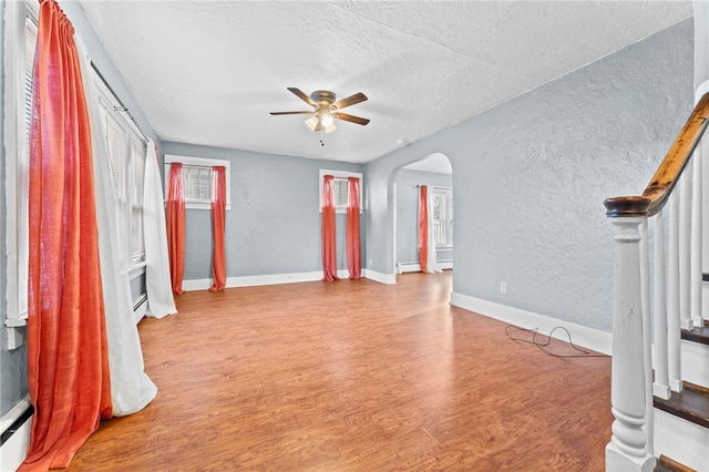 interior space with ceiling fan, baseboard heating, a textured ceiling, and light hardwood / wood-style flooring