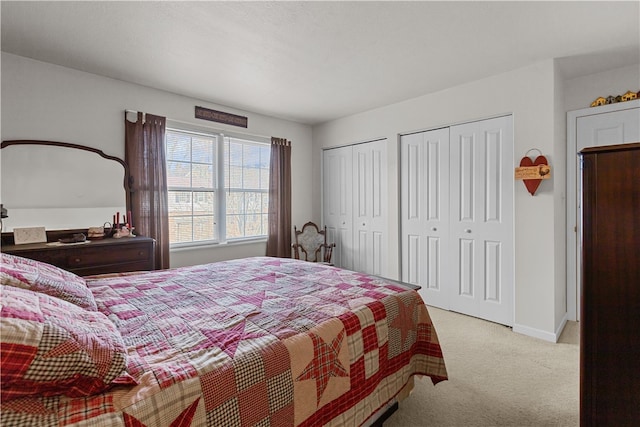 bedroom with multiple closets and light colored carpet