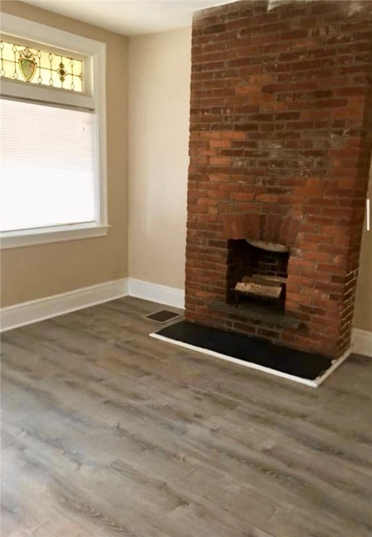 unfurnished living room featuring a fireplace and dark hardwood / wood-style floors