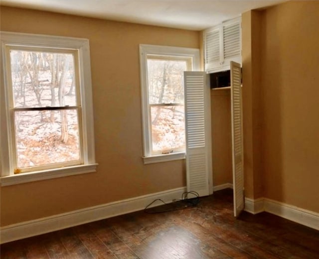 unfurnished bedroom featuring dark hardwood / wood-style flooring, a closet, and multiple windows