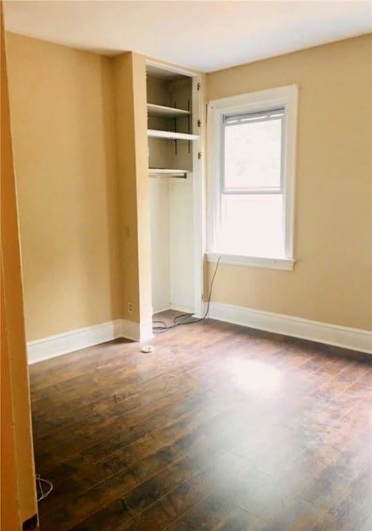 unfurnished bedroom with a closet and dark hardwood / wood-style flooring