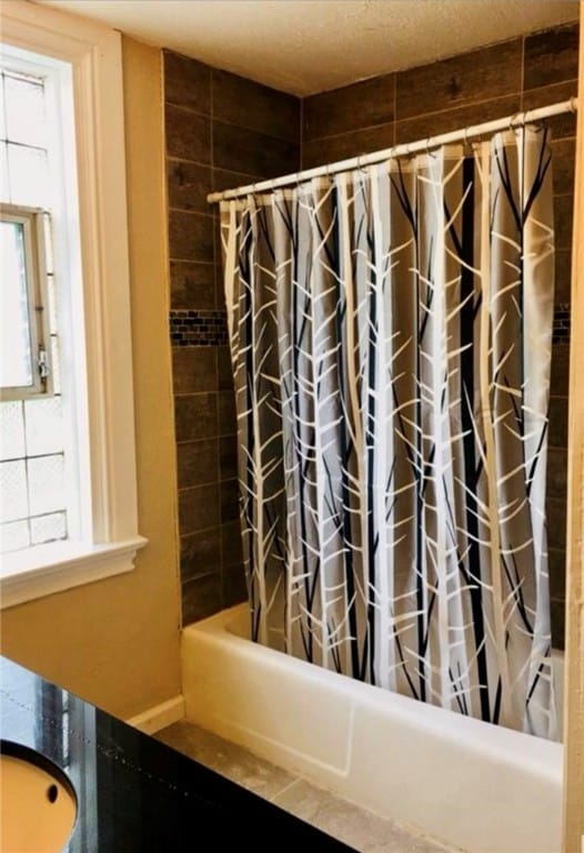 bathroom featuring sink, shower / bath combination with curtain, and a healthy amount of sunlight