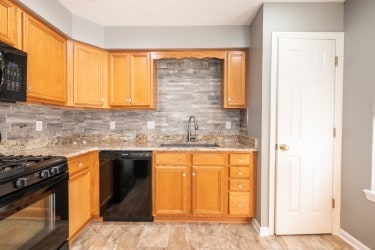 kitchen featuring decorative backsplash, black appliances, and sink