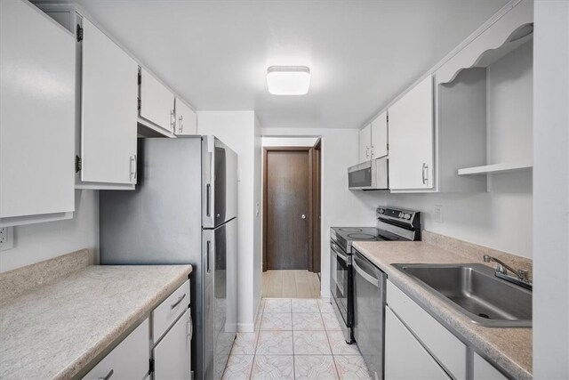 kitchen featuring stainless steel appliances, white cabinets, sink, and light tile patterned floors