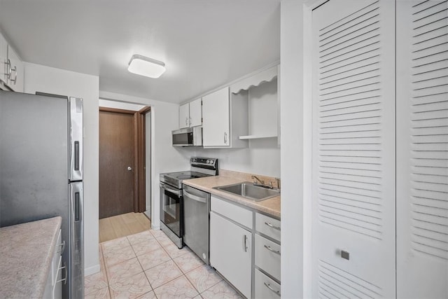 kitchen with white cabinets, appliances with stainless steel finishes, sink, and light tile patterned floors