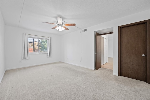 carpeted spare room featuring ceiling fan and a textured ceiling