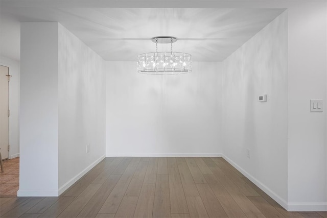 empty room featuring hardwood / wood-style flooring and an inviting chandelier