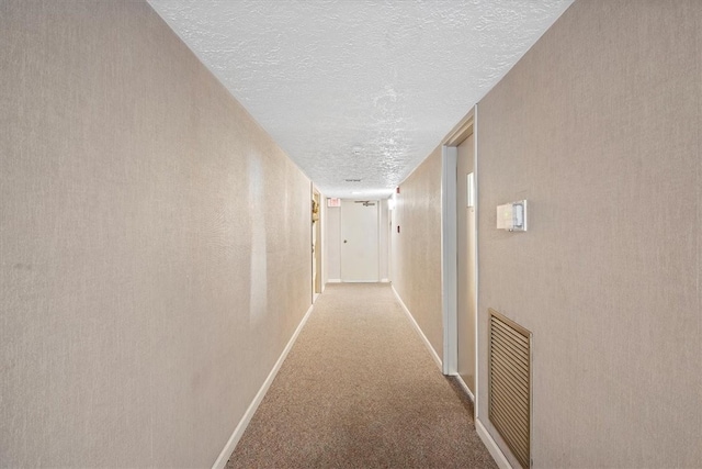 corridor featuring a textured ceiling and light carpet