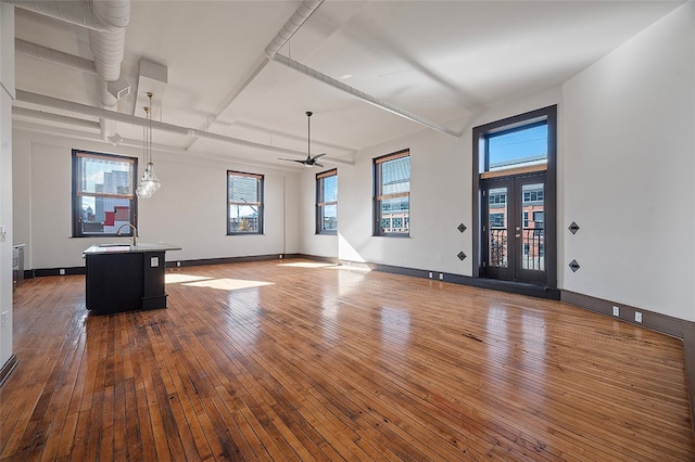 unfurnished living room with dark wood-type flooring, sink, and ceiling fan