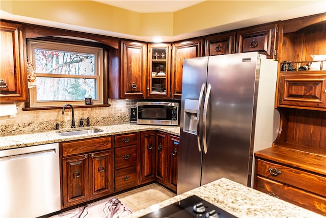 kitchen with stainless steel appliances, sink, light stone counters, tasteful backsplash, and light tile patterned floors