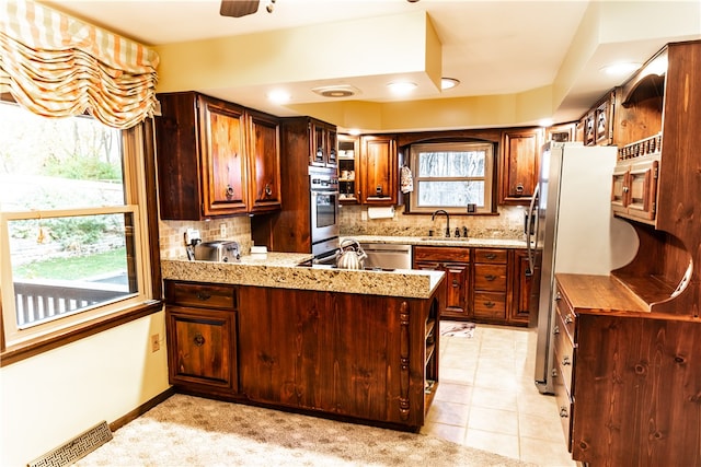 kitchen with decorative backsplash, kitchen peninsula, appliances with stainless steel finishes, and a healthy amount of sunlight