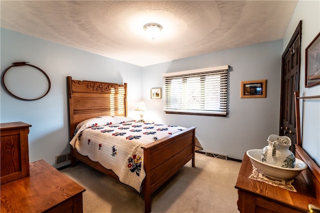 bedroom featuring light colored carpet and a textured ceiling