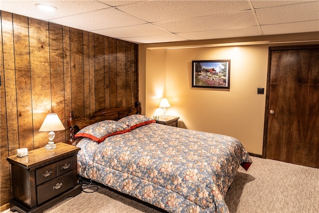 bedroom with a paneled ceiling, wooden walls, and carpet floors