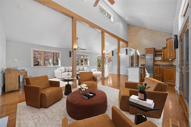 living room with ceiling fan, light wood-type flooring, high vaulted ceiling, and decorative columns