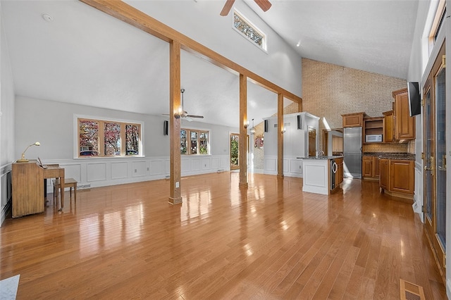 living room with high vaulted ceiling, ornate columns, ceiling fan, and light hardwood / wood-style flooring