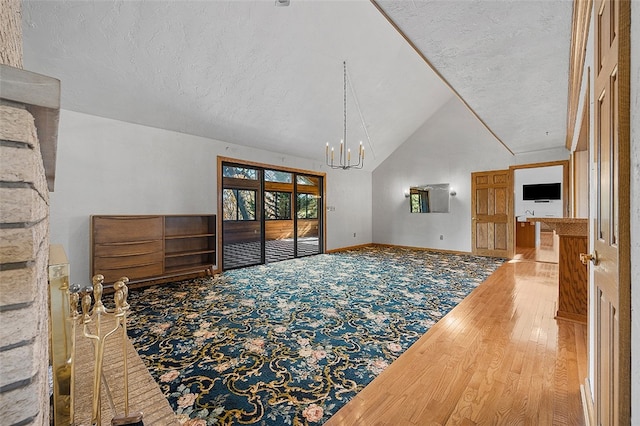 living room with wood-type flooring, a textured ceiling, high vaulted ceiling, and a notable chandelier