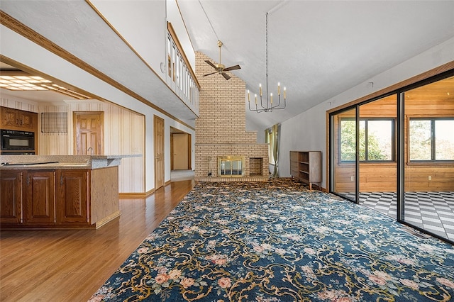 unfurnished living room with light wood-type flooring, wooden walls, crown molding, and a brick fireplace