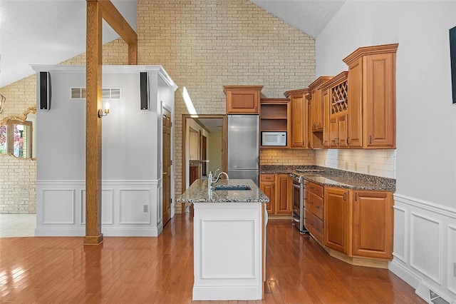 kitchen featuring sink, appliances with stainless steel finishes, vaulted ceiling, and brick wall