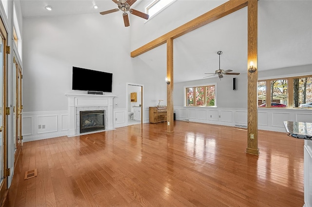 unfurnished living room with high vaulted ceiling, light hardwood / wood-style flooring, ceiling fan, and a premium fireplace