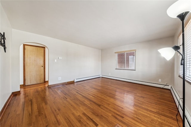 spare room with a baseboard heating unit and wood-type flooring