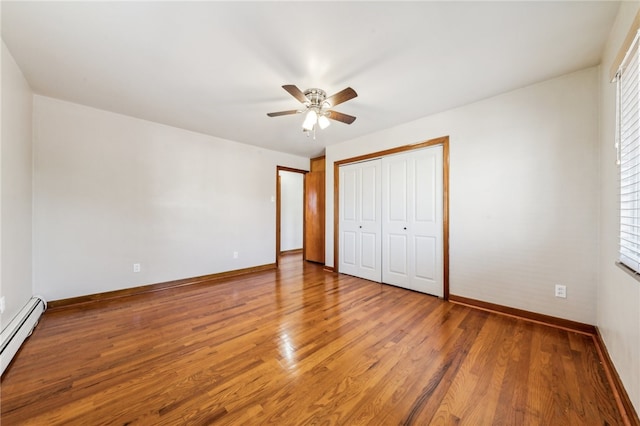 unfurnished bedroom with a closet, hardwood / wood-style floors, ceiling fan, and a baseboard radiator