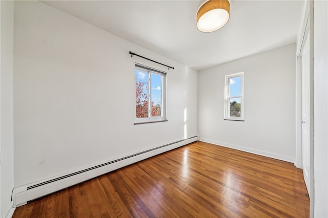 empty room with hardwood / wood-style flooring, plenty of natural light, and a baseboard radiator