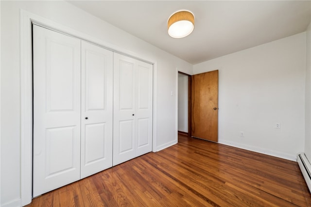 unfurnished bedroom with dark hardwood / wood-style flooring, a closet, and a baseboard radiator