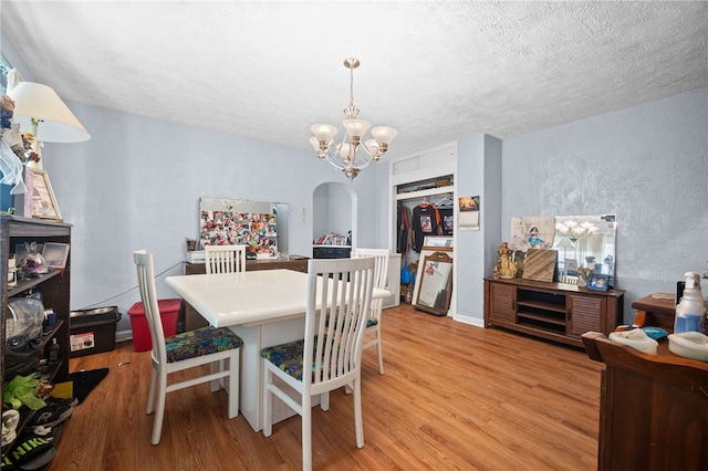 dining room featuring a textured ceiling, light hardwood / wood-style flooring, and a chandelier