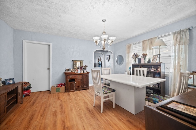 dining room featuring light hardwood / wood-style floors, a textured ceiling, and a notable chandelier