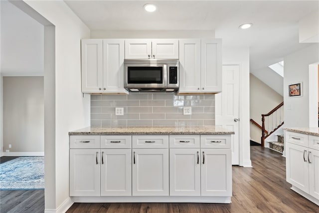 kitchen featuring white cabinets, light stone countertops, and dark hardwood / wood-style floors