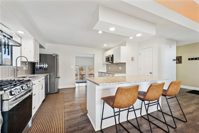 kitchen with tasteful backsplash, white cabinetry, appliances with stainless steel finishes, sink, and dark wood-type flooring