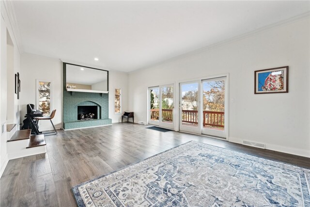 living room featuring a brick fireplace, wood-type flooring, and ornamental molding