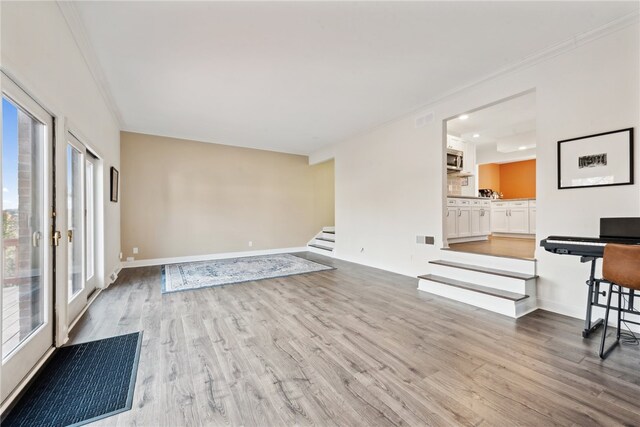 unfurnished living room featuring light hardwood / wood-style floors and crown molding