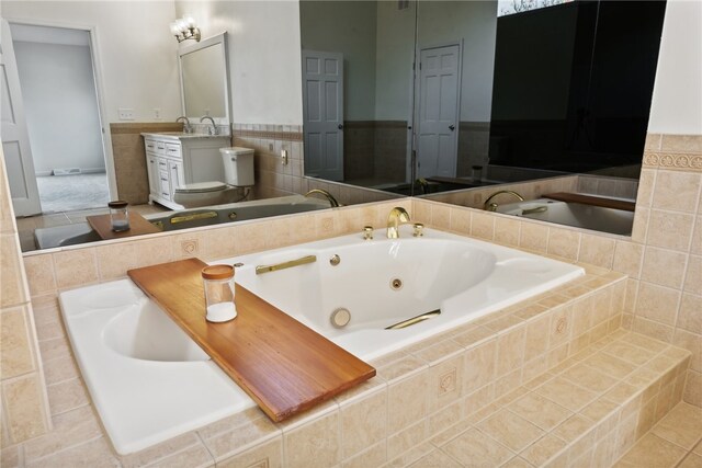 bathroom with toilet, vanity, and tiled tub