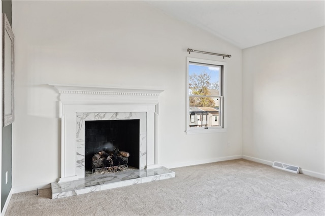 unfurnished living room featuring vaulted ceiling, light colored carpet, and a fireplace