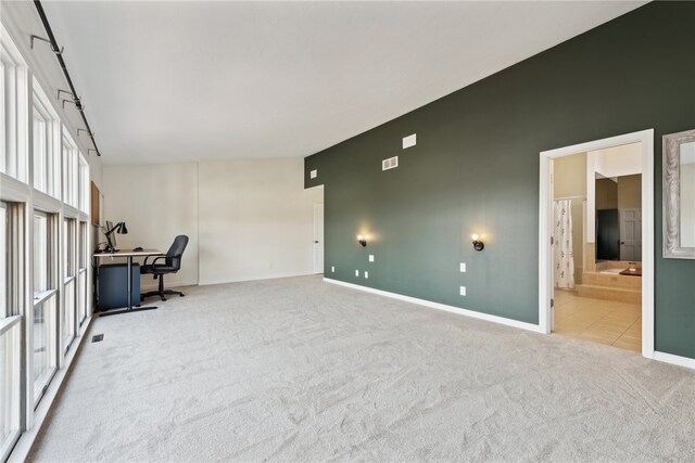 interior space featuring a towering ceiling and light colored carpet