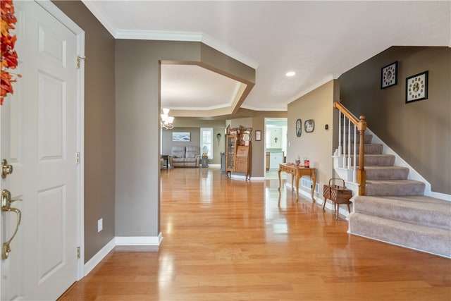 foyer featuring light wood-type flooring, a notable chandelier, and ornamental molding