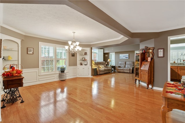 dining space featuring a chandelier, sink, crown molding, light wood-type flooring, and built in features