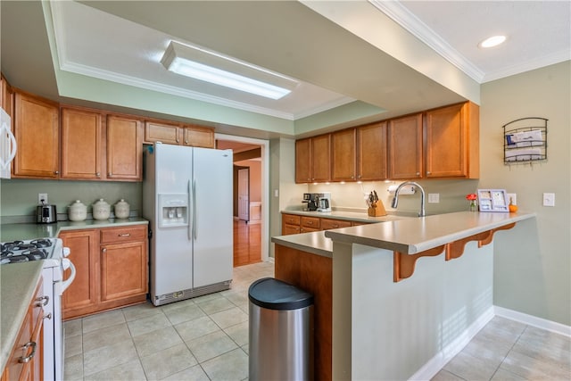 kitchen featuring kitchen peninsula, a kitchen breakfast bar, light tile patterned floors, white appliances, and crown molding