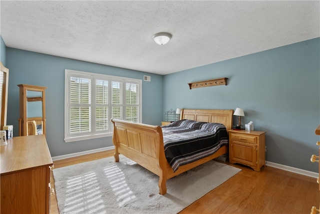 bedroom with light hardwood / wood-style floors and a textured ceiling