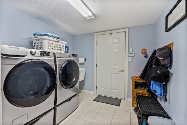 laundry room with washing machine and dryer, a textured ceiling, and light tile patterned flooring