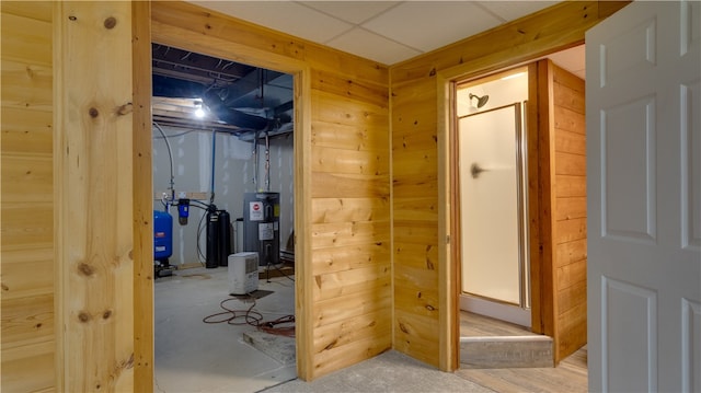 hall with water heater, wood walls, and concrete flooring