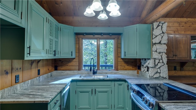 kitchen featuring stainless steel appliances, wood walls, sink, green cabinetry, and pendant lighting