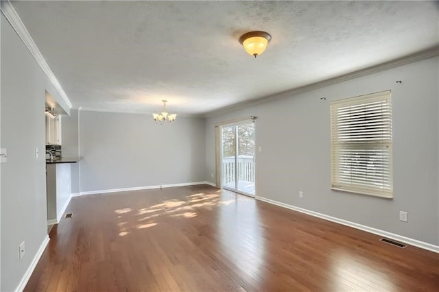 unfurnished living room with dark wood-type flooring, an inviting chandelier, and crown molding