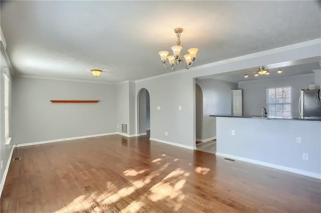 spare room with a chandelier, crown molding, and dark hardwood / wood-style flooring