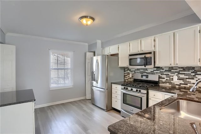 kitchen with stainless steel appliances, white cabinetry, sink, and tasteful backsplash