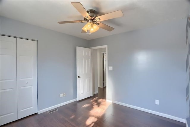 unfurnished bedroom featuring dark hardwood / wood-style flooring, ceiling fan, and a closet